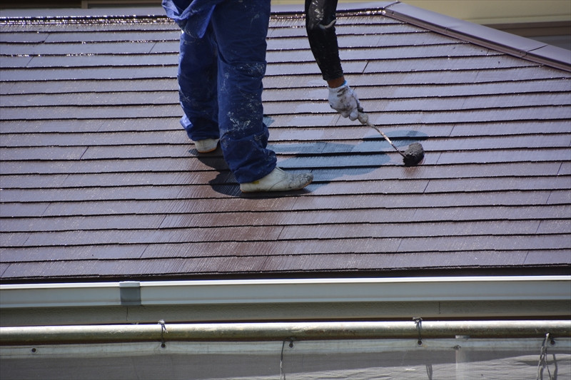 ローラーで屋根の塗り替えを行う職人